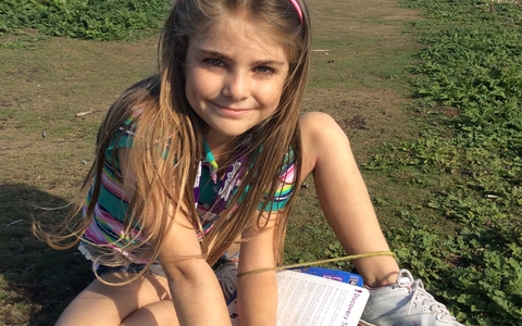 Grace sits in the grass with flowers