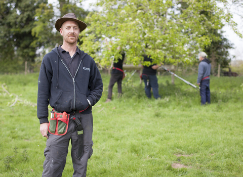 Laurence standing in an orchard