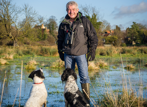 Tony stands in a wetland with his dogs